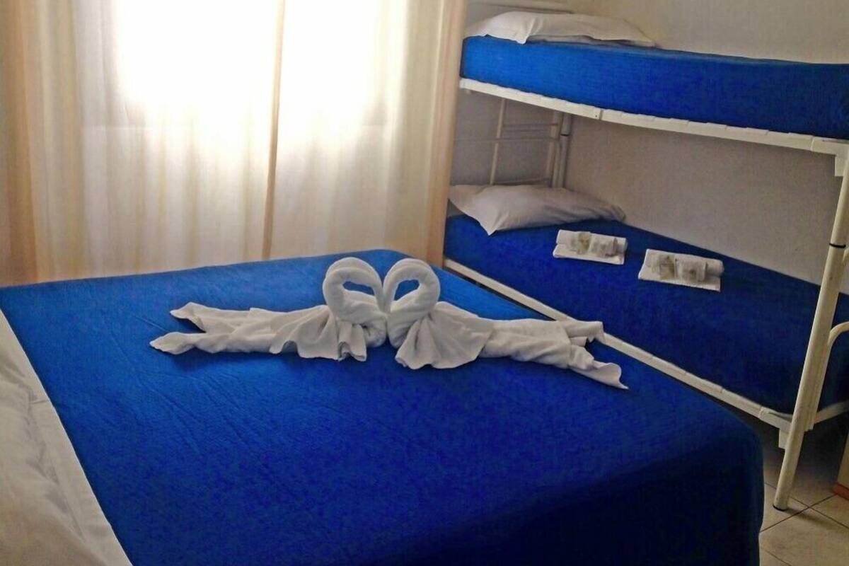 A hotel room with two bunk beds, a blue bedspread, and a towel arrangement on the lower bed.