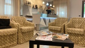 Un vestíbulo de hotel con sofás estampados, un mostrador de recepción y revistas sobre una mesa.