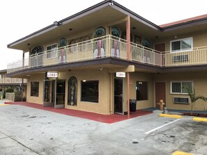 Un edificio de dos pisos con toldo rojo, un balcón con barandillas blancas y dos letreros que dicen 'Lobby'.