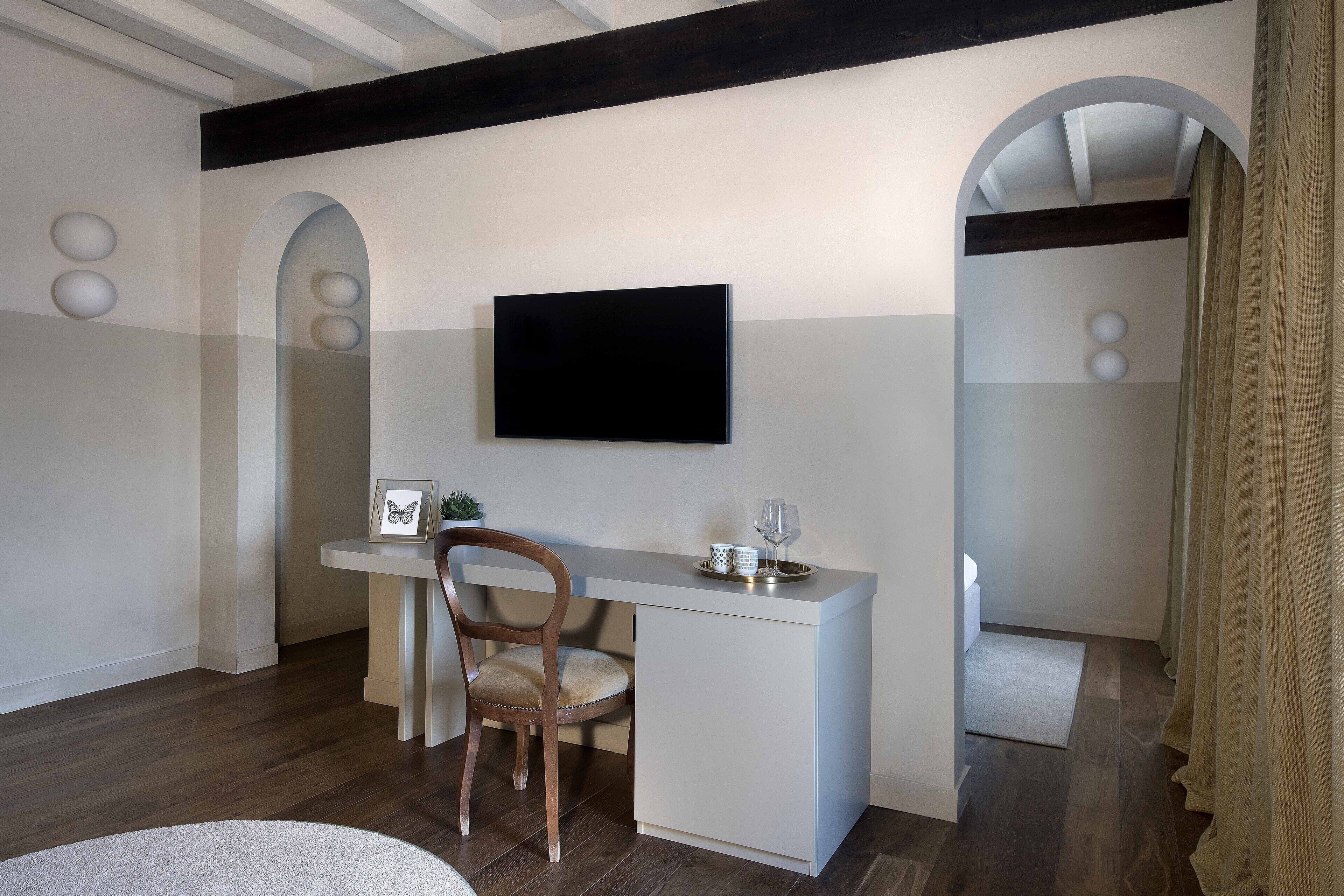 Habitació moderna amb escriptori, cadira i televisió de pantalla plana penjada a la paret.