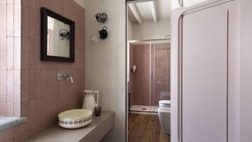 A bathroom with a sink, mirror, and shower.