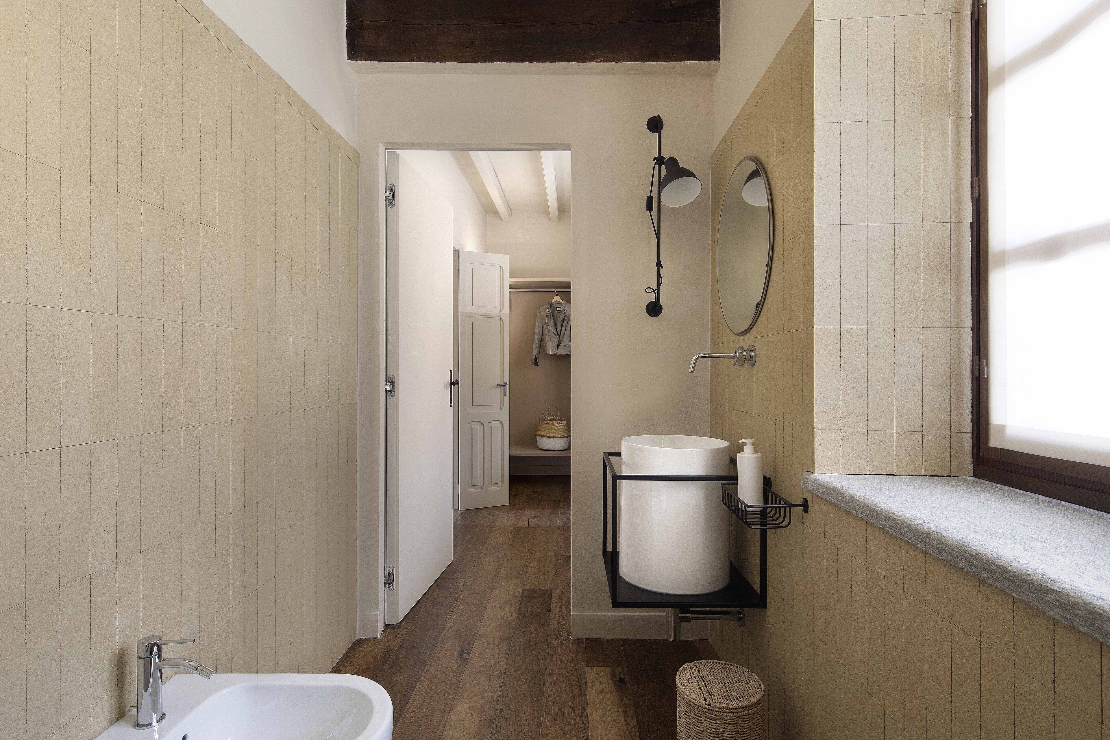 A narrow bathroom with a white sink, a mirror, and a towel rack.