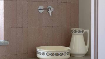 Un baño con lavamanos, espejo y jarra.