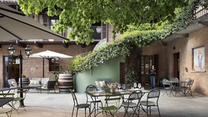 An outdoor patio area with tables and chairs, a brick wall, and a staircase. - Agriturismo Ca' del Re (Verduno)