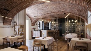 A restaurant with brick ceilings, wooden tables, and a kitchen in the background. - Agriturismo Ca' del Re (Verduno)