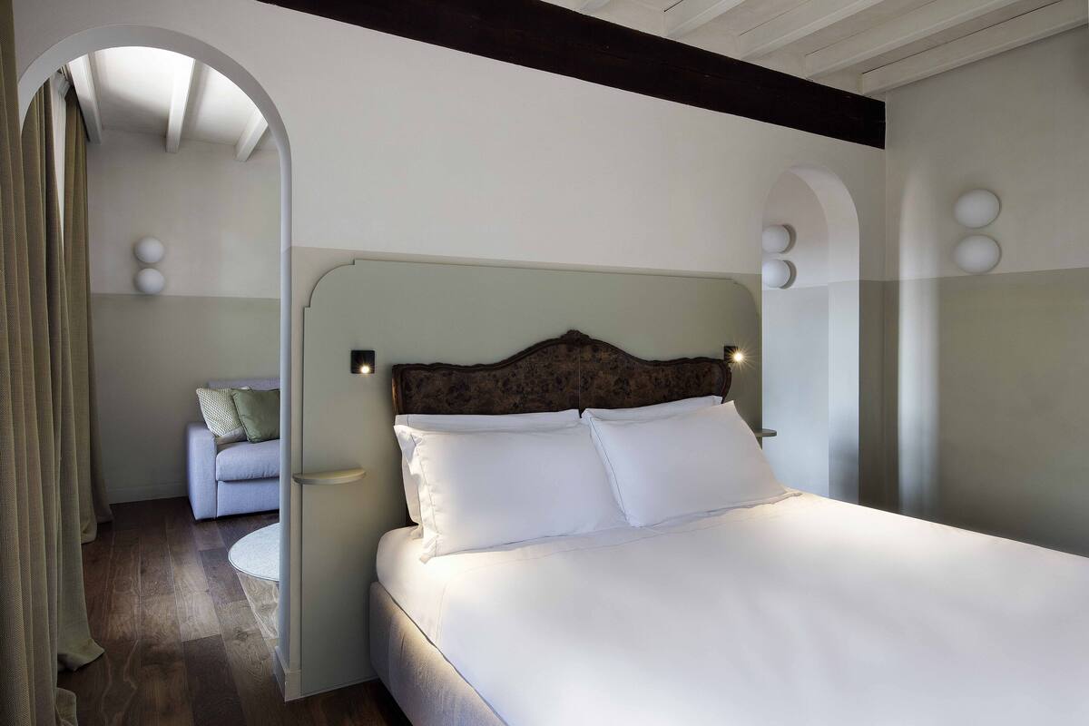 A bedroom with a large bed, a wooden headboard, and a round bedside table.