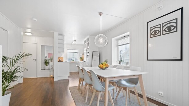 Una cucina moderna con mobili bianchi, un'area pranzo con tavolo e sedie bianche, e un'ampia finestra che offre luce naturale.