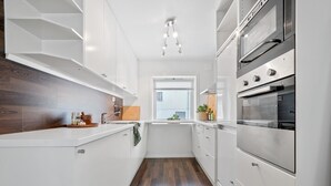 Una cucina moderna con mobili bianchi, elettrodomestici in acciaio inossidabile e pavimento in legno.