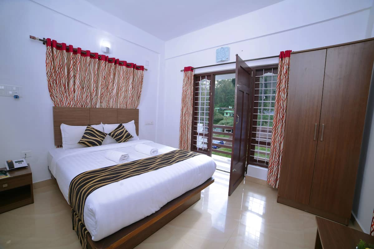 A hotel room with a large bed, wooden headboard, and a view through the open door.