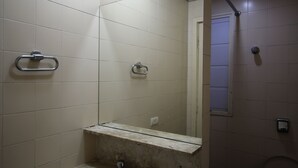 Une salle de bain avec des murs carrelés de carreaux blancs, un lavabo avec un miroir et un porte-serviettes.