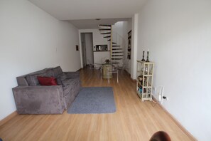 A living room with a grey sofa, a small round table, and a staircase leading to another level.