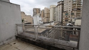 Un balcon doté d’une rambarde en métal, d’où l’on peut admirer un paysage urbain avec de nombreux immeubles de grande hauteur.