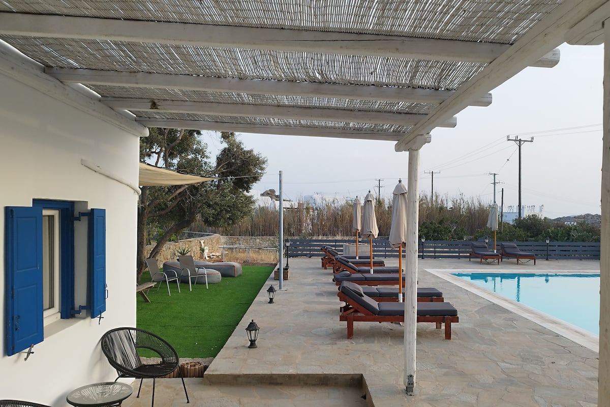 A covered outdoor area with a pool, lounge chairs, and a small garden.
