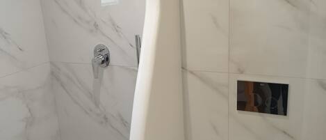 A modern bathroom with a curved shower enclosure, a toilet, and a control panel on the wall.