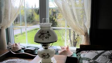 A room with a window, a lamp, a doily, a shell, and a quilted pillow.
