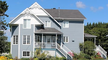 Stylish two-story house with a steeply pitched roof and decorative trim, set amidst a beautifully landscaped garden.