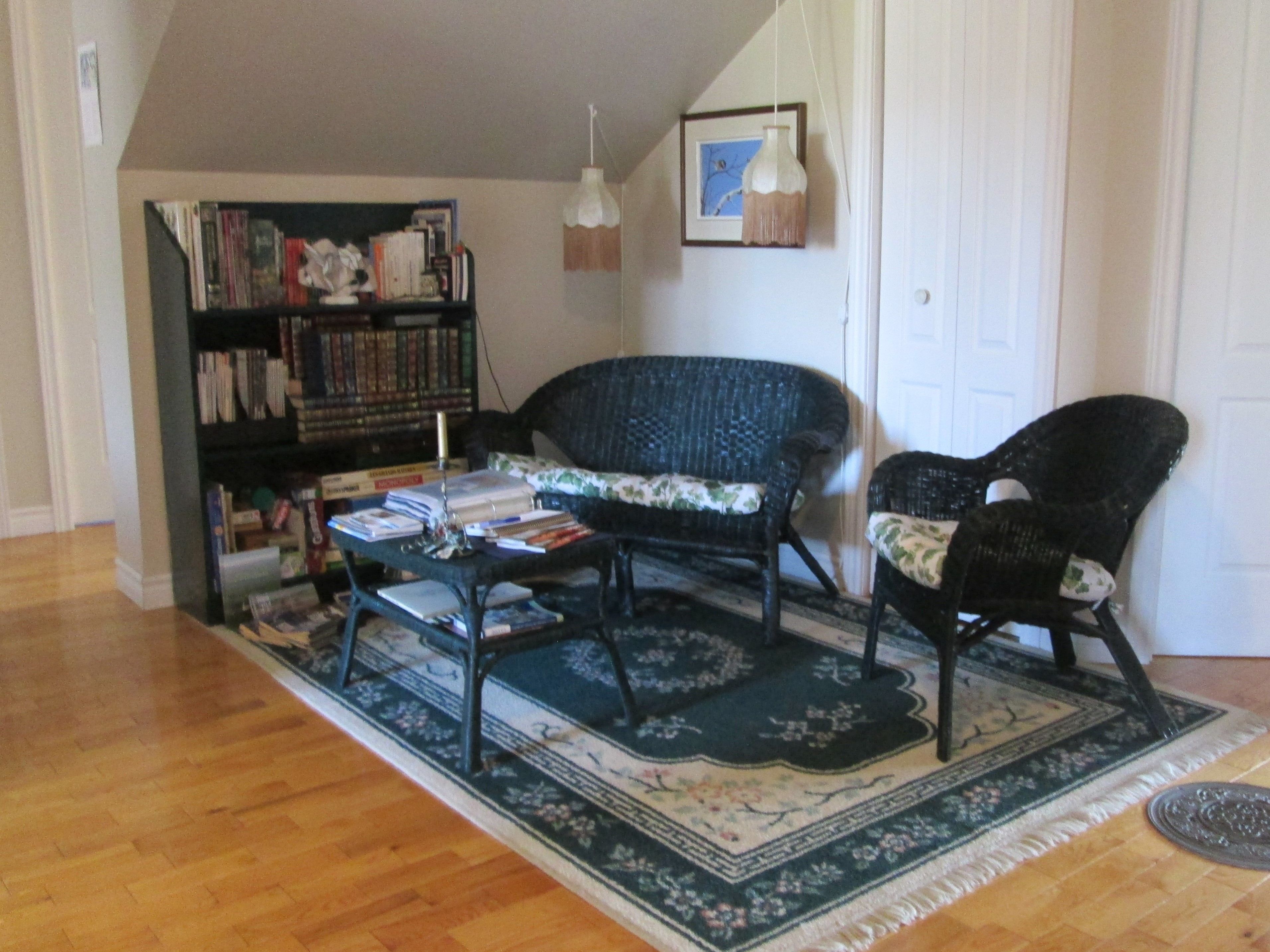 A living room with a bookshelf, two chairs, a coffee table, and a rug.