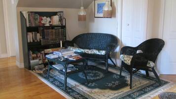 A living room with a bookshelf, two chairs, a coffee table, and a rug.