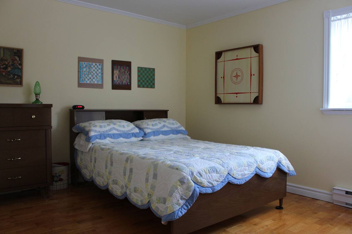 Un dormitorio con una cama de madera, un aparador y un ventanal.