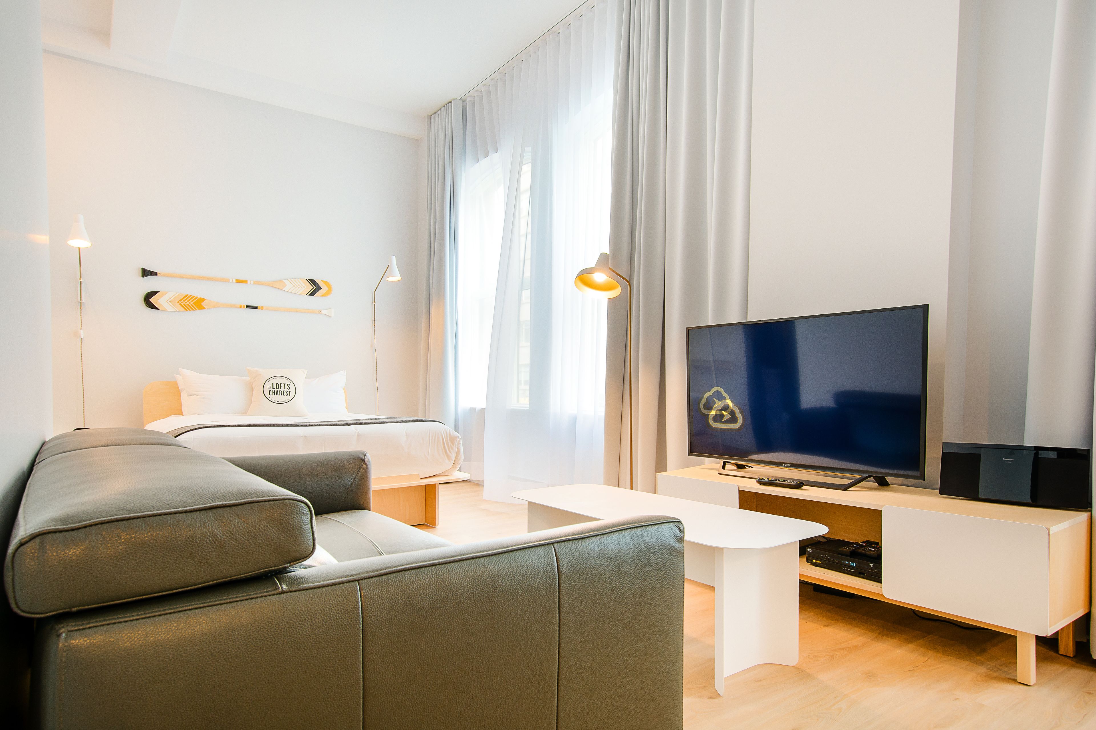 Una habitación de hotel moderna con cama, sofá, televisor y escritorio.