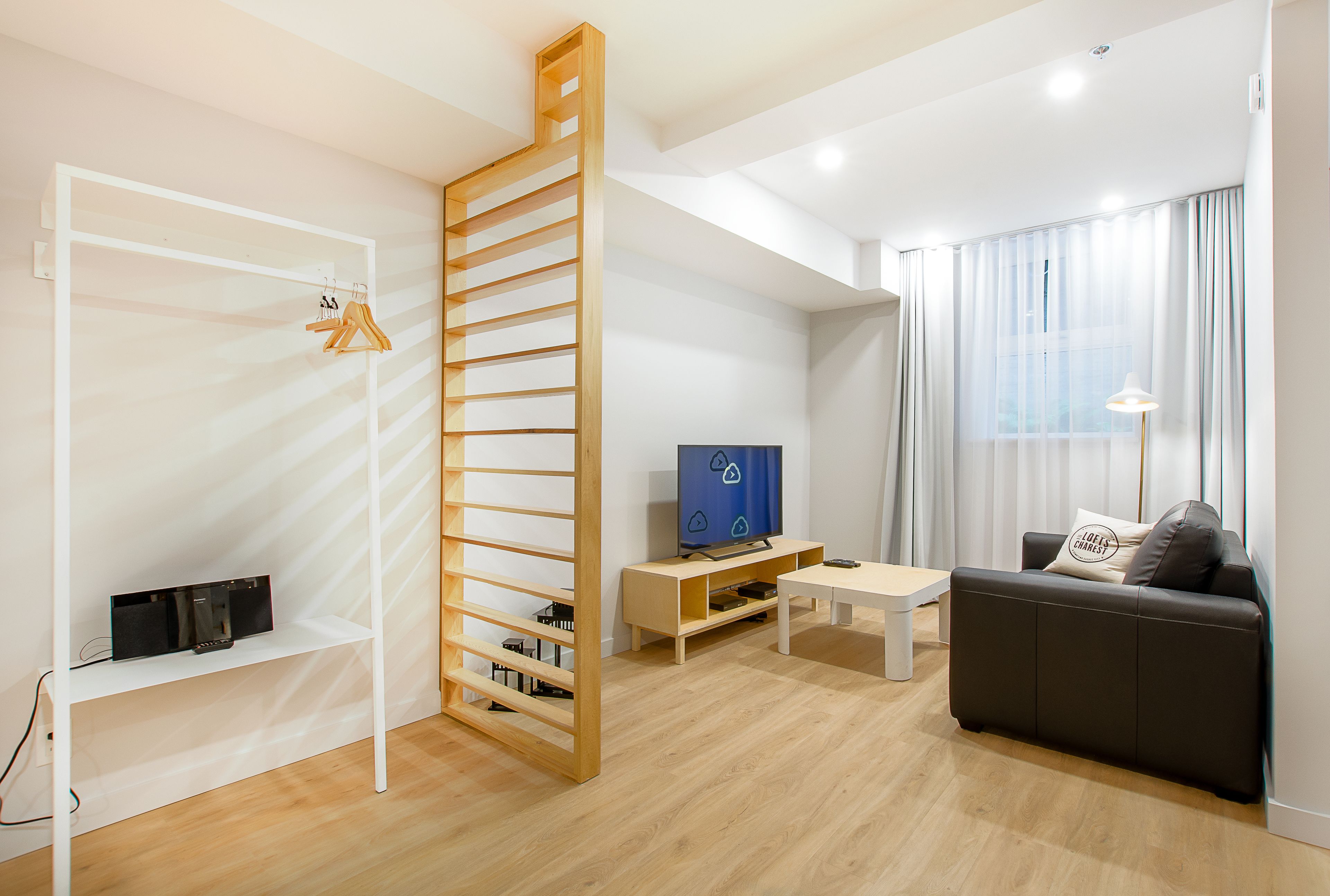 A modern living room with a wooden TV stand, a sofa, and a white shelving unit.