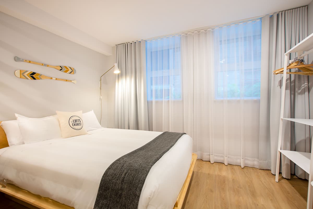 A neatly made bed with a grey throw blanket, a pillow with a logo, and two paddle-shaped wall decorations.