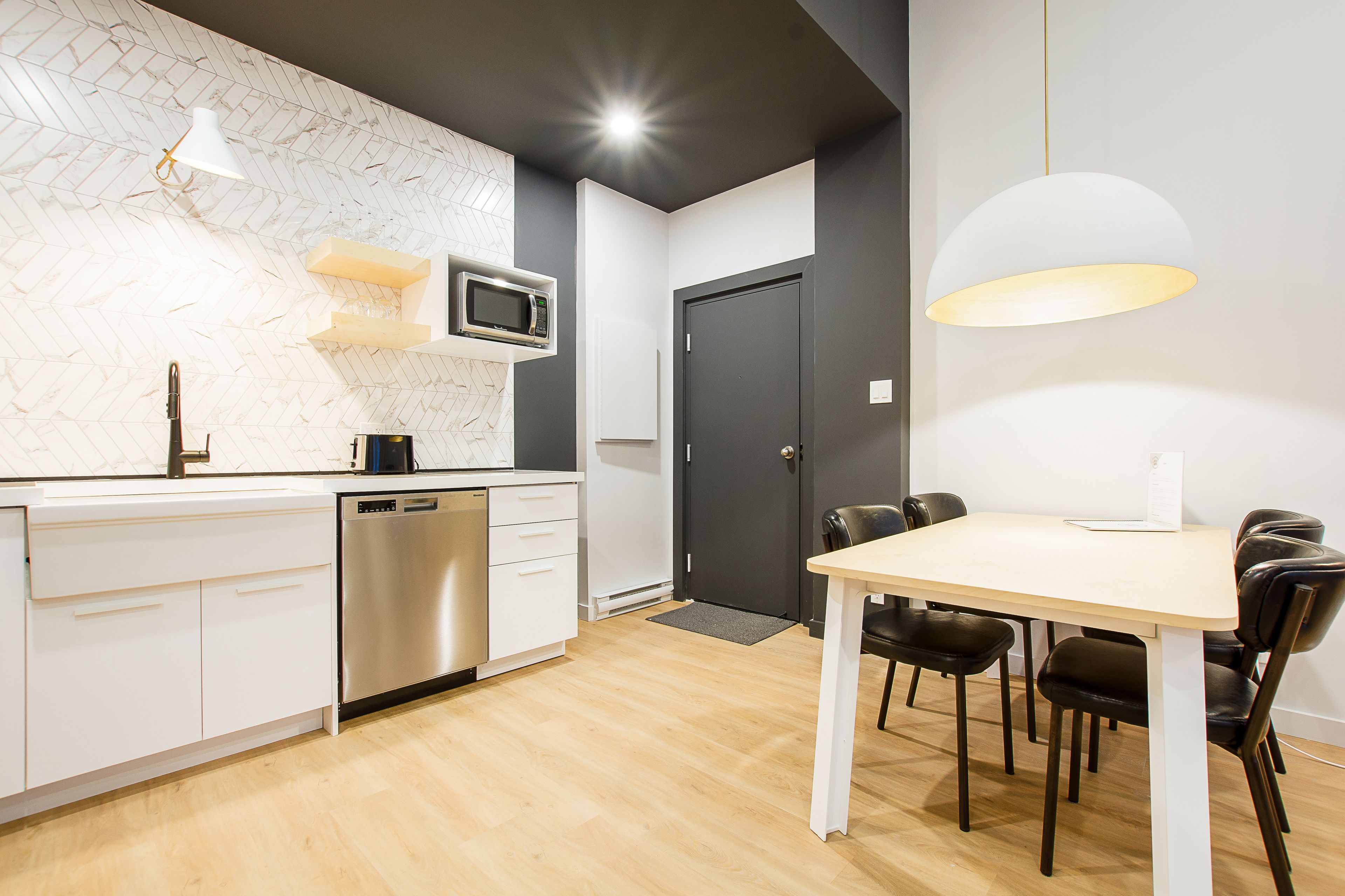 Una cocina moderna con armarios blancos, microondas integrado y un comedor con mesa y sillas.