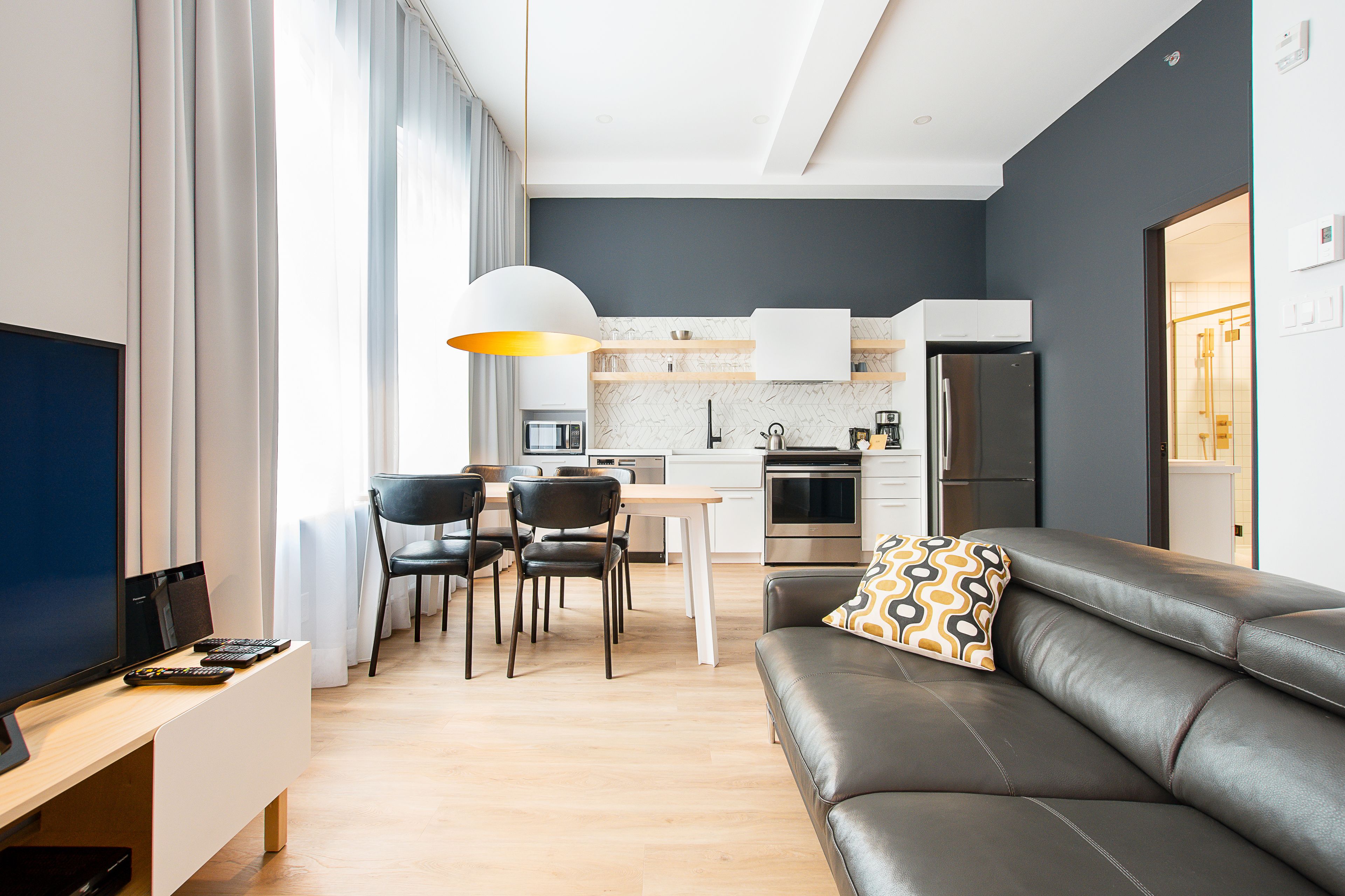 En moderne stue med sofa, fjernsyn og spiseområde med stole og bord.