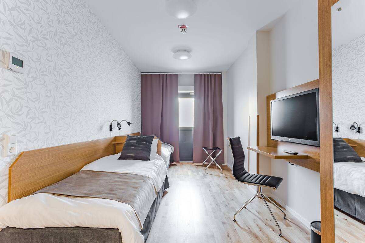 Une chambre d’hôtel moderne équipée de deux lits, d’une télévision et d’un bureau.