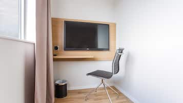 A modern room with a mounted TV, a chair, and a trash bin.