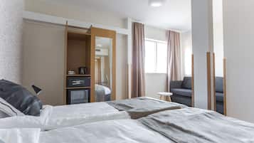 Habitación de hotel con dos camas, un escritorio, una silla, un armario y una ventana con cortinas.
