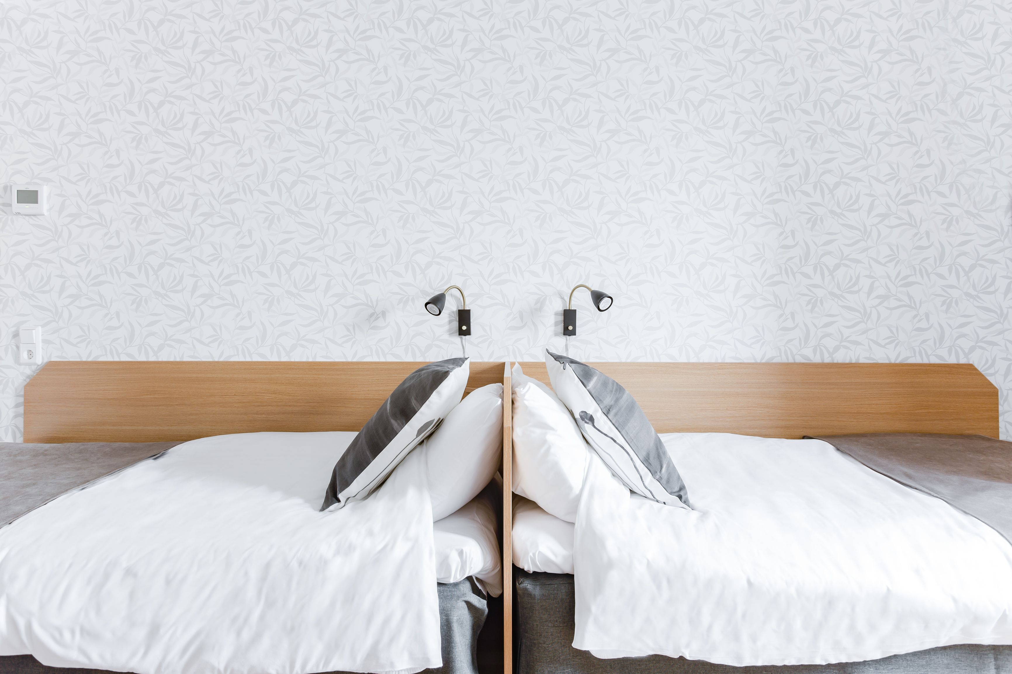 Una cama doble con cabecera de madera, dos almohadas y una manta.