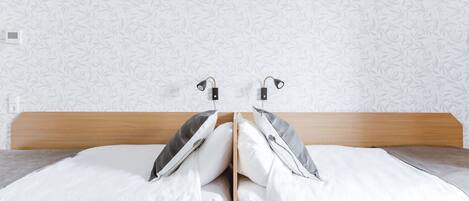 Una cama doble con cabecera de madera, dos almohadas y una manta.