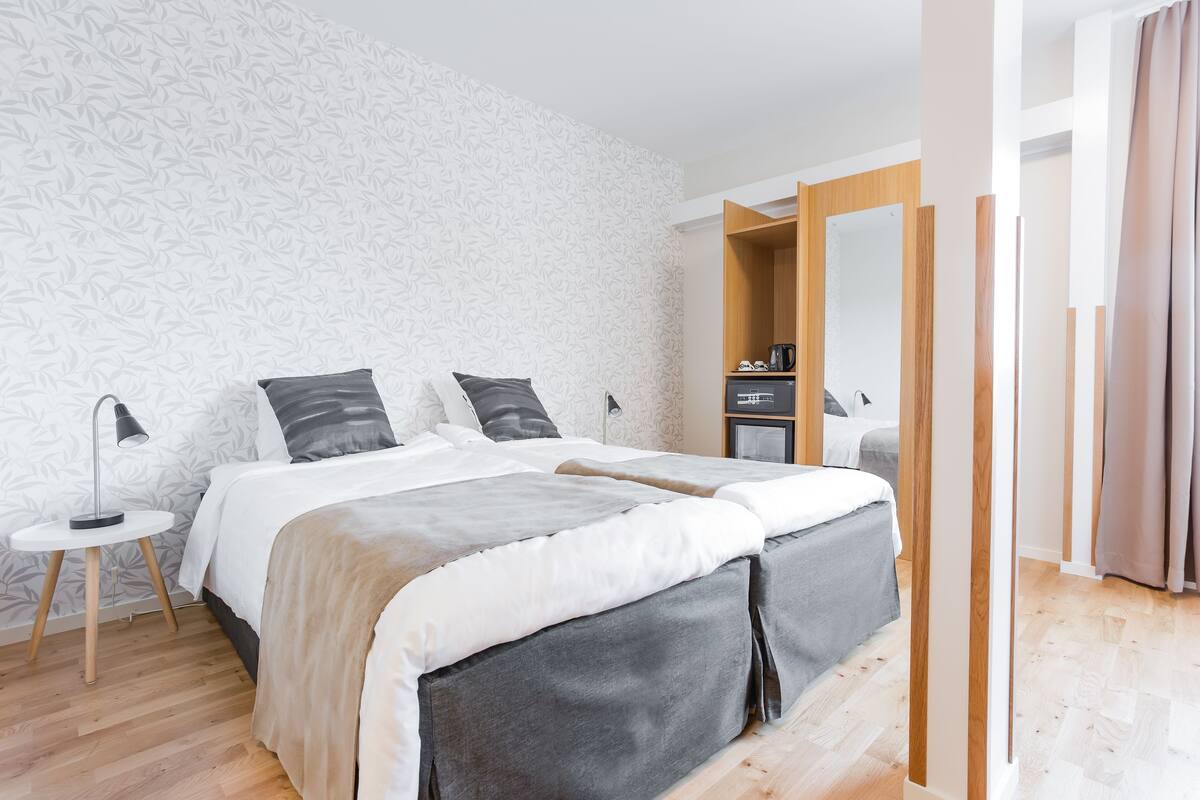 Une chambre moderne avec un grand lit, une table de chevet, une commode et un miroir.