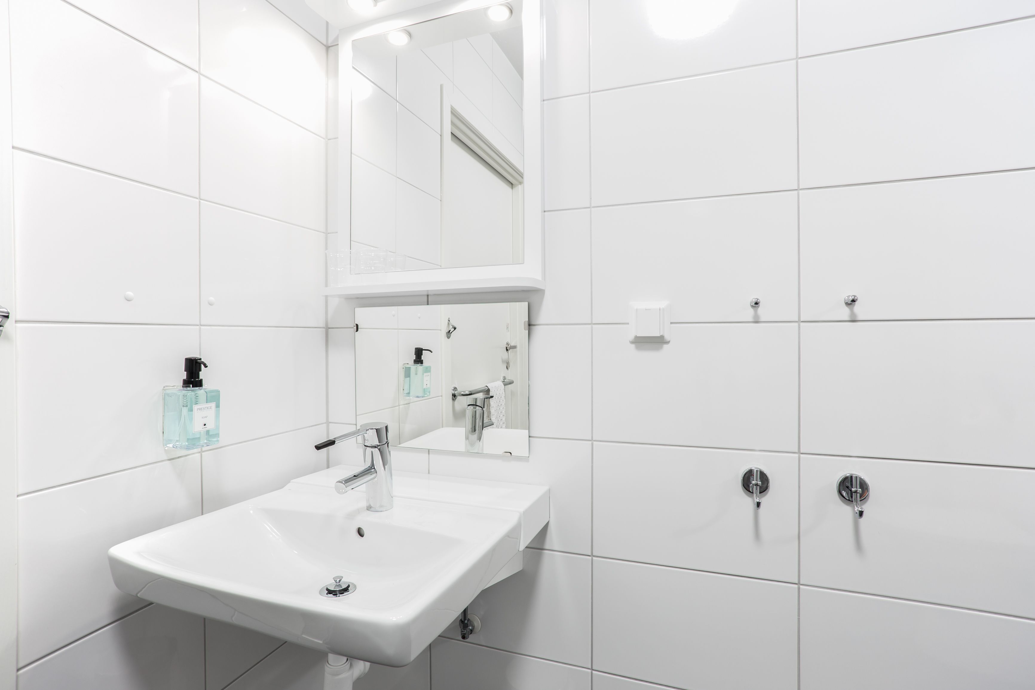 A modern bathroom with a white sink, mirror, and two towel racks.