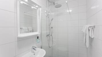 A modern bathroom with a glass-enclosed shower, a white sink, and a mirror above the sink.
