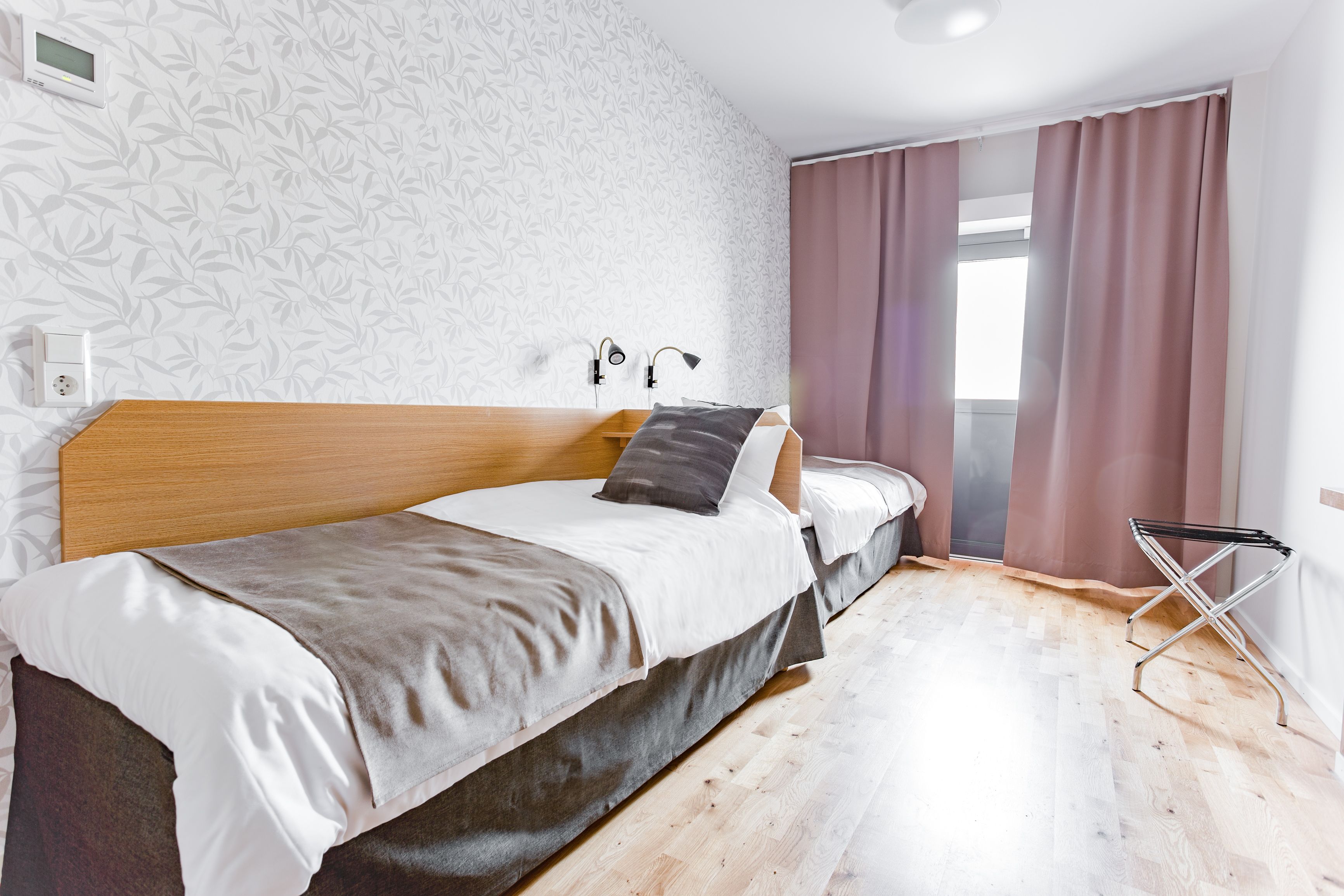 A neatly made bed with a wooden headboard, a bedside table, and a wall-mounted light.