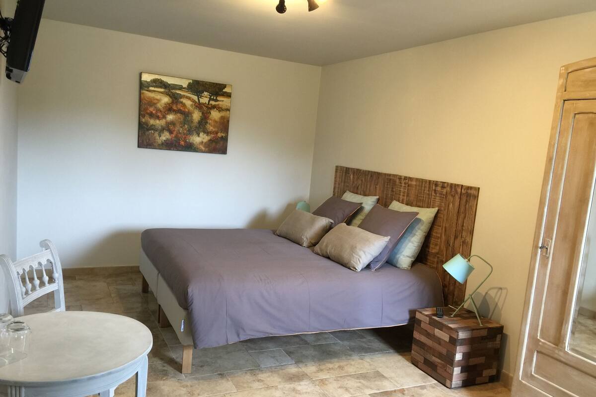 Ein Schlafzimmer mit einem Bett, einem Sessel, einem Tisch und einem Bild an der Wand.
