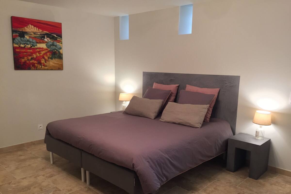 Ein Schlafzimmer mit einem Bett, zwei Nachttischlampen, einem Nachttisch, einem Bild an der Wand und einem kleinen Oberlicht.