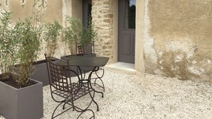 A rustic outdoor seating area with a table and chairs, surrounded by potted plants. - La Rivayne (Lauris)