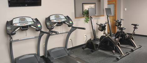 Un gimnasio con cintas de correr, elípticas y bicicletas estáticas.