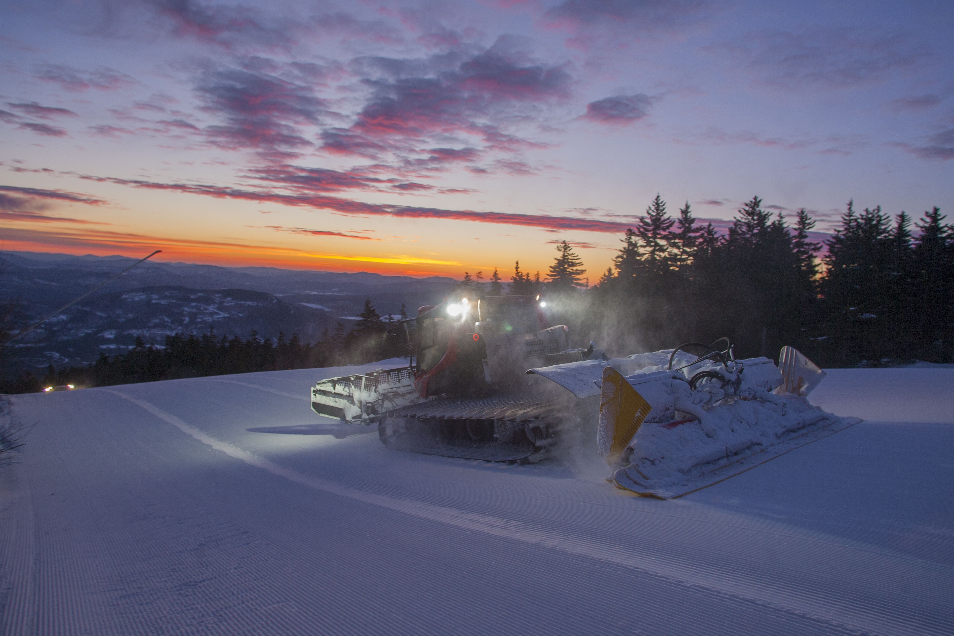 A snow-covered landscape with a snowmobile and a sled.
