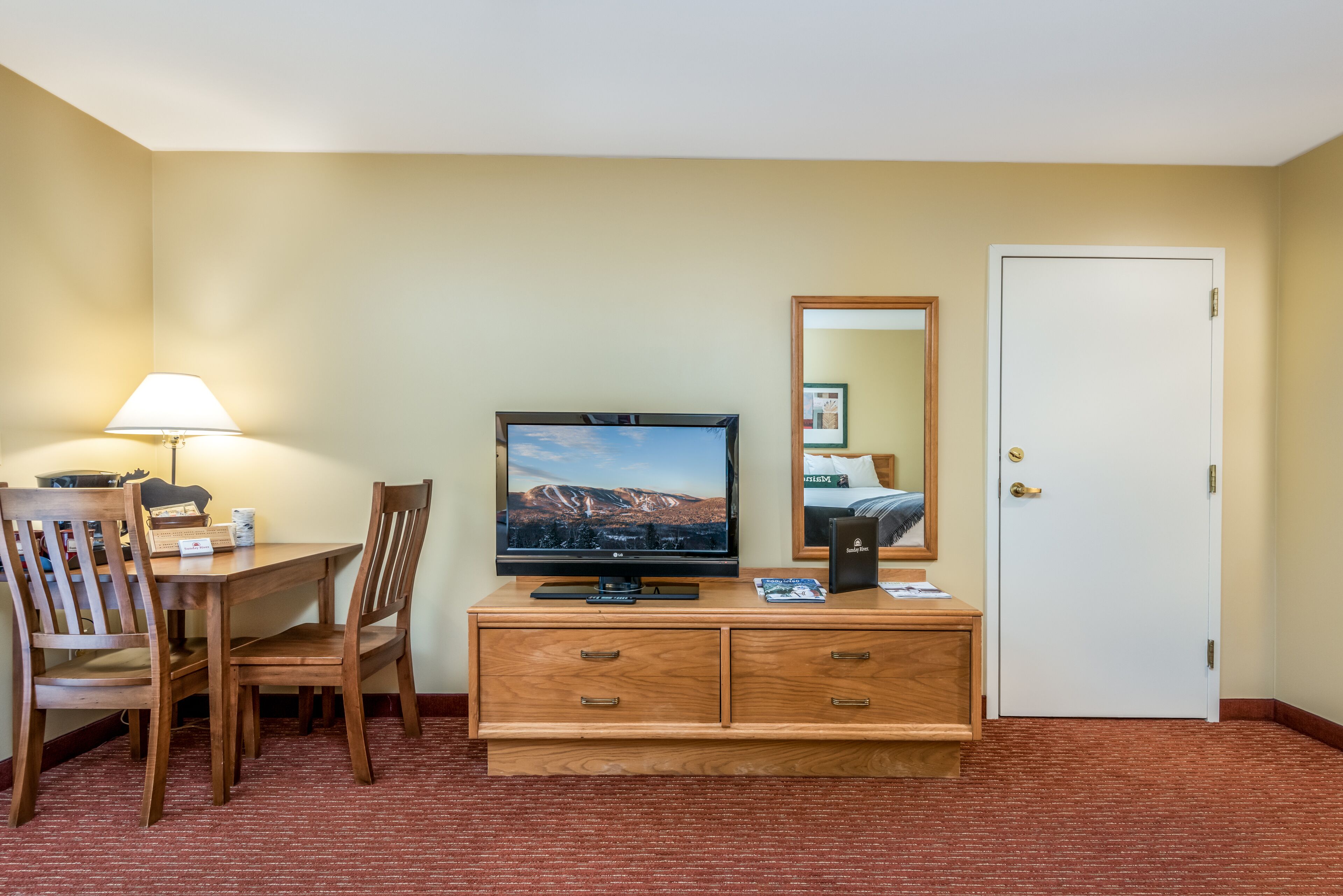 Une chambre d’hôtel avec un bureau en bois, une télévision et un miroir.