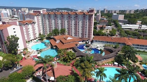A hotel with multiple swimming pools, palm trees, and a mountainous backdrop. - Agape - Hot Springs Apart Hotel (Caldas Novas)