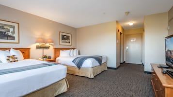 A hotel room with two beds, a TV, a desk, and a lamp.