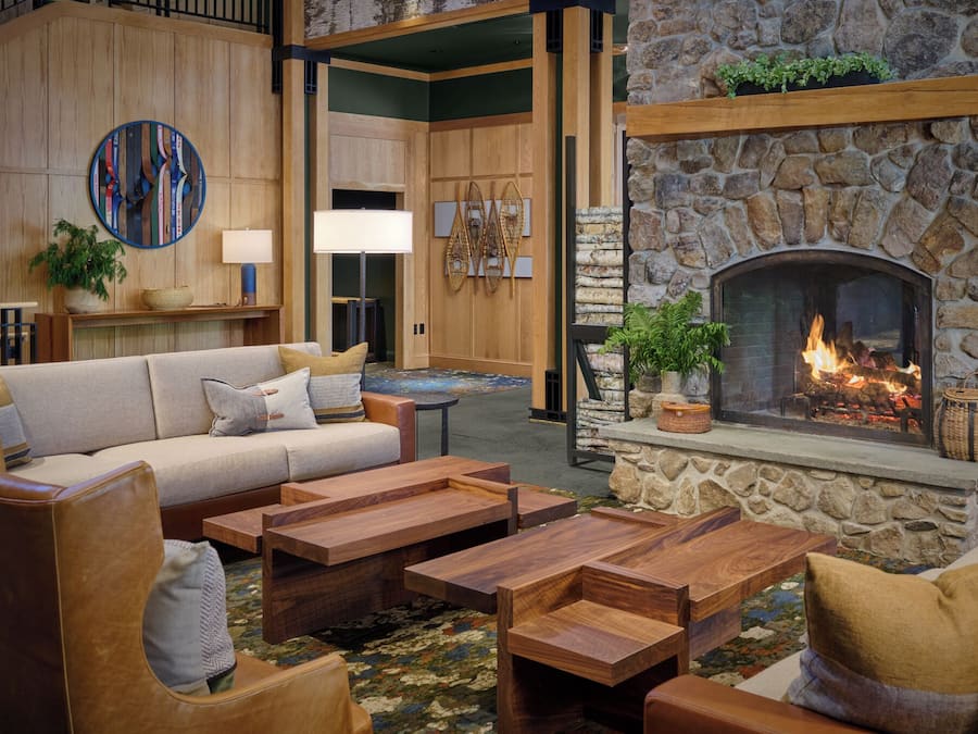 A cozy lobby with a stone fireplace, wooden furniture, and a large sofa.