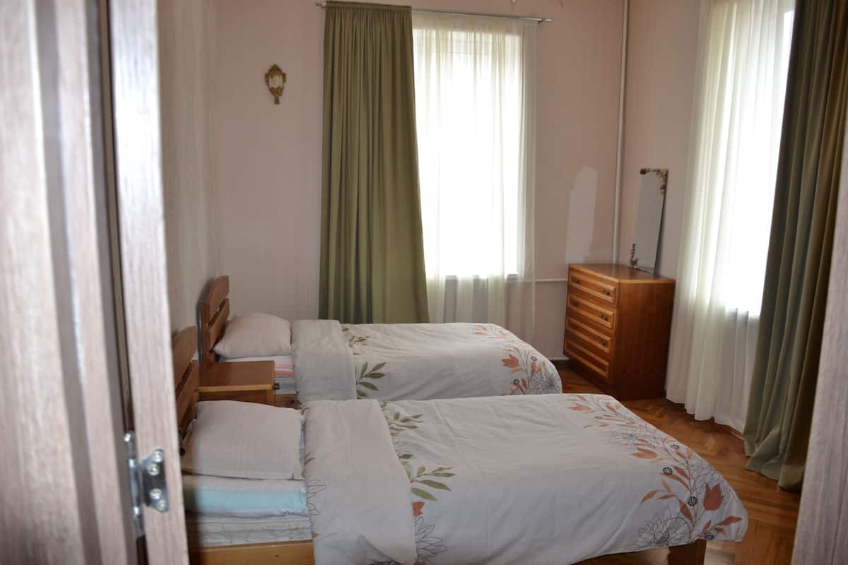 Un dormitorio con dos camas individuales, un aparador de madera y un espejo.