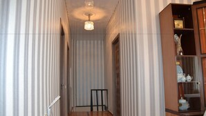 Un couloir étroit aux murs recouverts d’un papier peint à rayures, doté d’un plancher en bois et agrémenté d’un lustre.