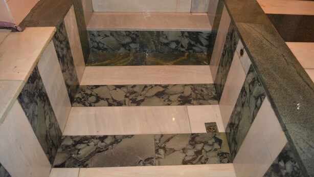Une salle de bain avec un sol en marbre, un lavabo et un miroir.
