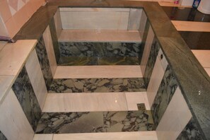 Un baño con piso de mármol, un lavamanos y un espejo.